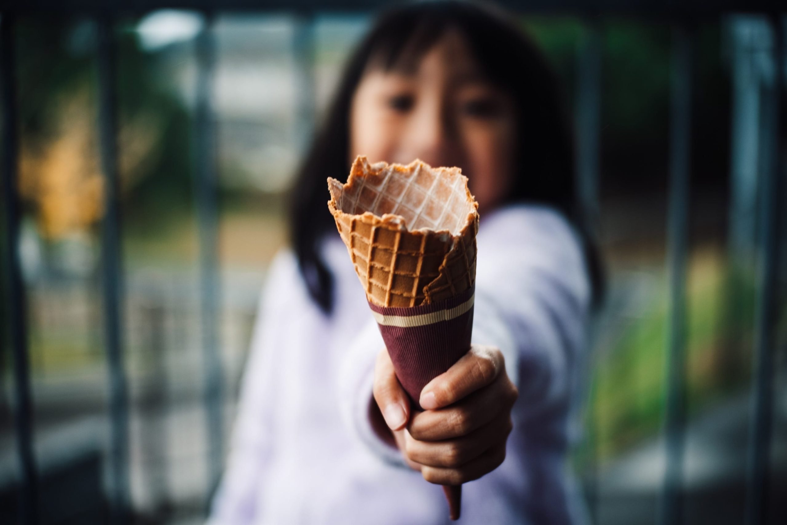 Meike 35mm f1.7 Sample Image of a girl holding a waffle cone up to the camera.