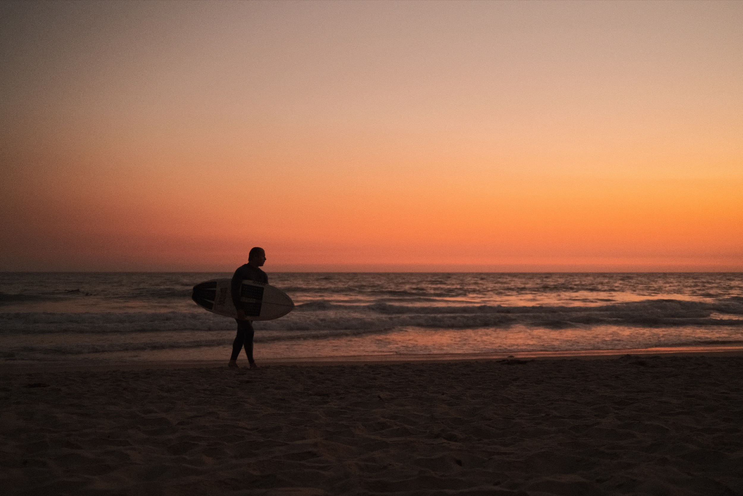 Surfer walks across beach at night