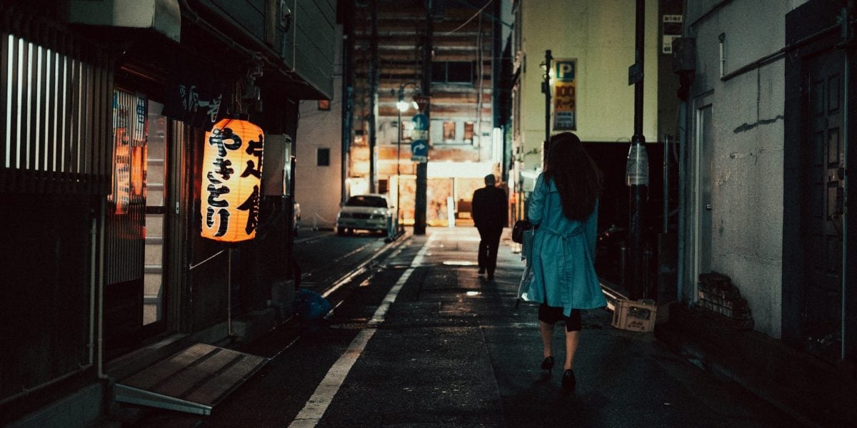 Woman walking down a long alley in the Nakasu Distract of Fukuoka.
