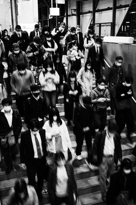 Slow Shutter black and white shot of crowd going down stairs at a train station.