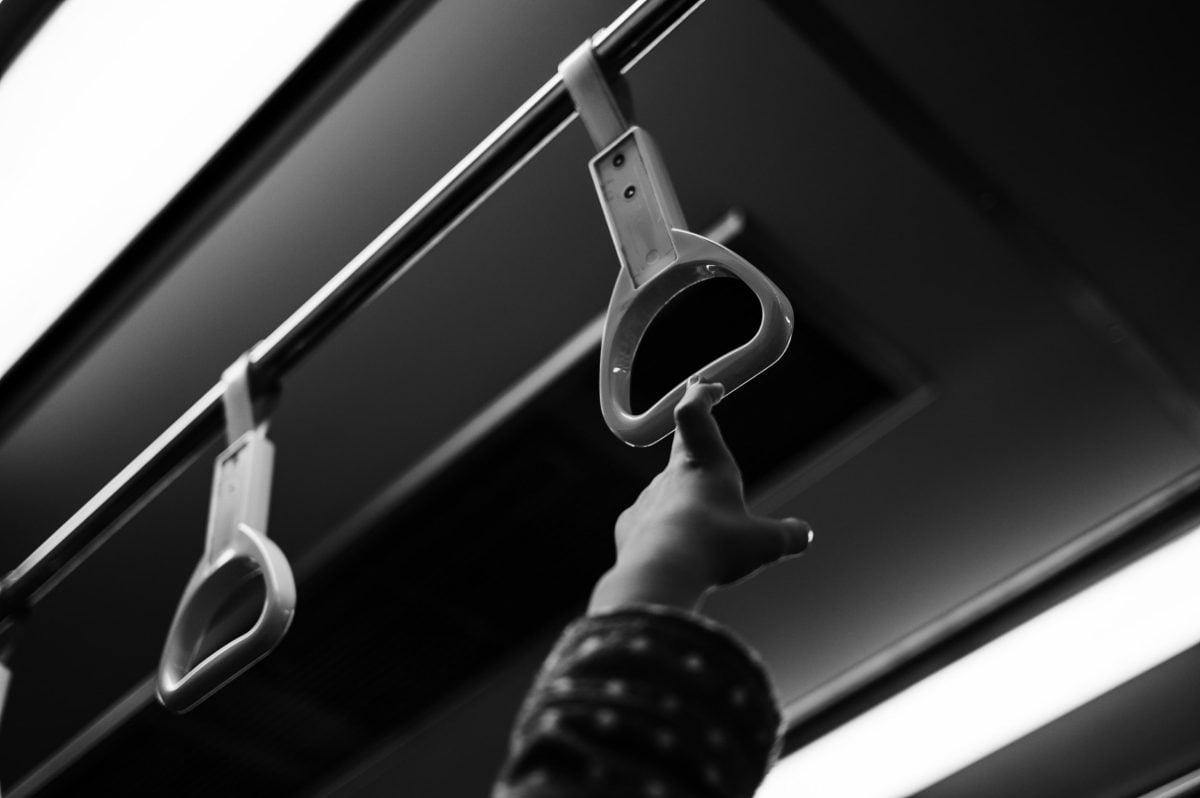 Small hand reaching for the hand grips on a subway train.
