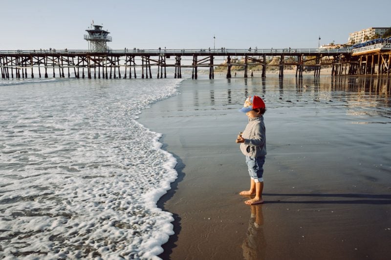 Boy playing on the beach at the San Clemente Pier.