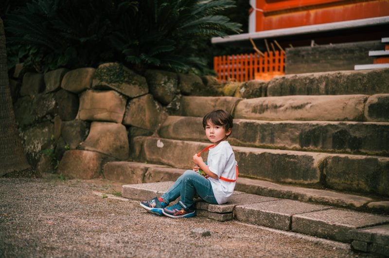 portrait of little boy at the base of stairs of a Japanese temple
