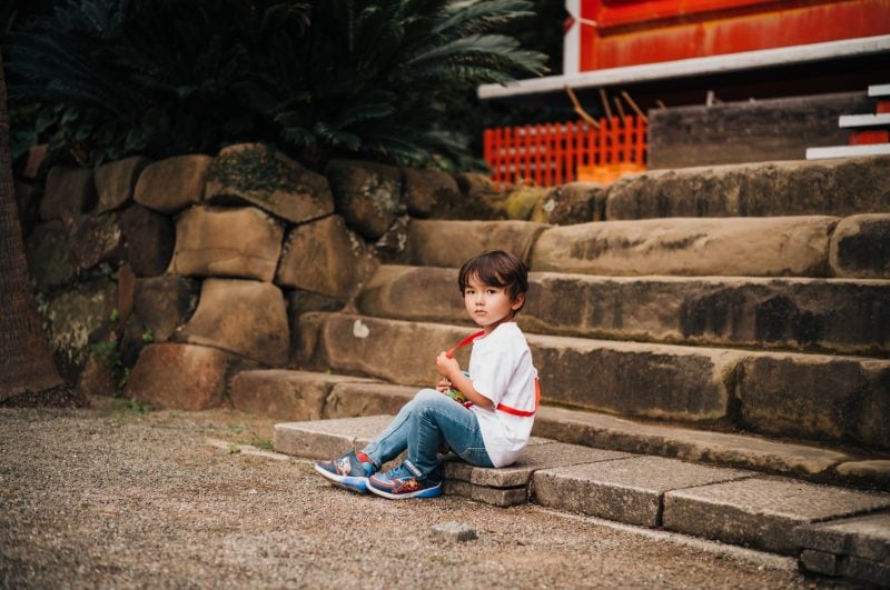portrait of boy sitting on stairs of a Japanese shrine